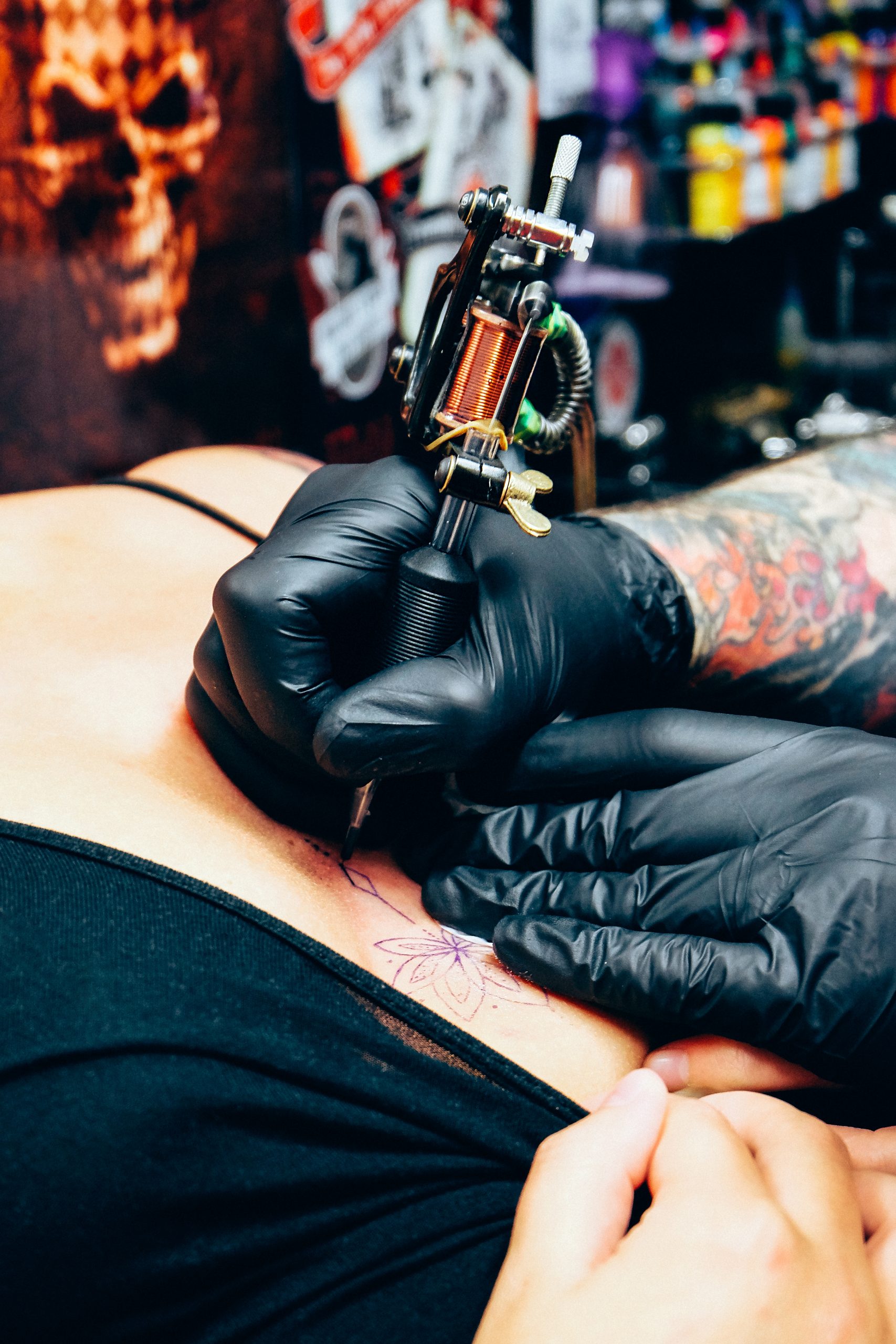 tattooist-tattooing-a-women-s-chest-with-gloves-an-2022-11-16-19-07-02-utc-scaled.jpg